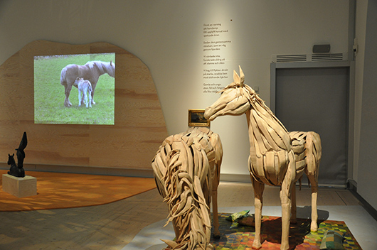 Till höger syns Christine Lundströms installation där två hästar av sammanfogade trästycken betar på ett lapptäcke.